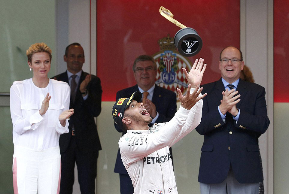 Lewis Hamilton throws his throphy into the air (Credit: Reuters)